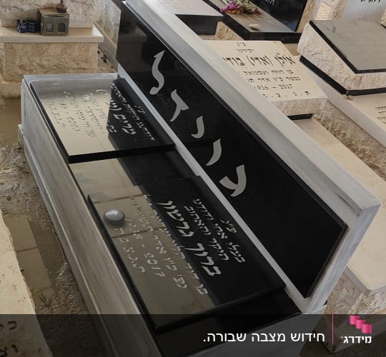 מצבות עם כיתוב בעברית, פרחים ואבנים מונחים עליהם